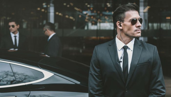 bodyguard standing at businessman car and reviewing territory